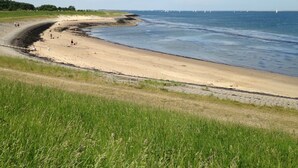 A beach with a curved shoreline, grassy areas, and a clear sky. - Nice house in Zeeland near the Oosterschelde (Kattendijke)