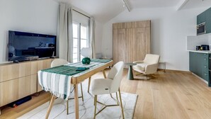 A modern living room with a dining area, a TV, and a kitchen area. - The On Cloud 9-Quiet & Renovated-by Mon Petit Faré (Paris)
