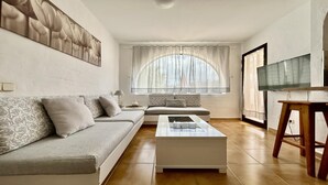 Una sala moderna con un sofá, una mesa de centro y un televisor.