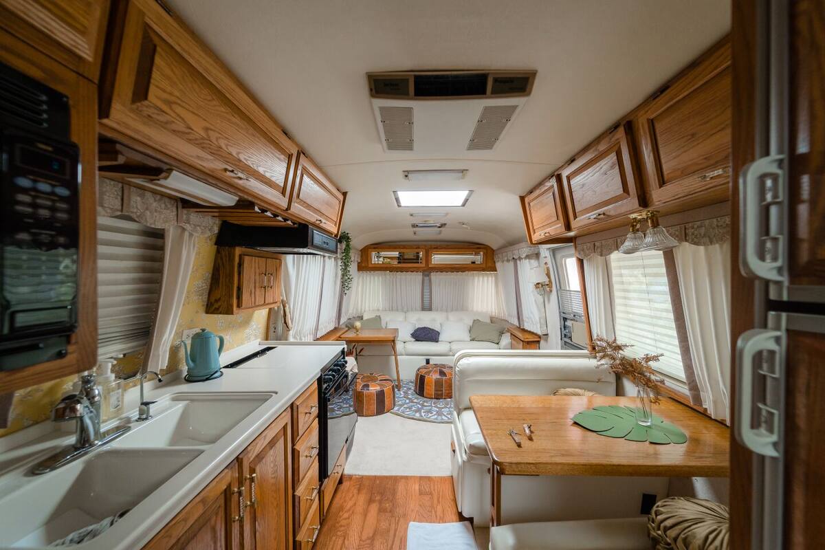A compact RV interior with a kitchenette, dining area, and seating space.
