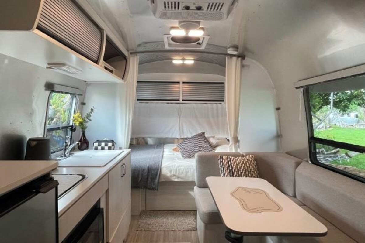 Un intérieur de camping-car compact comprenant un coin cuisine, un lit à baldaquin et un petit espace repas.