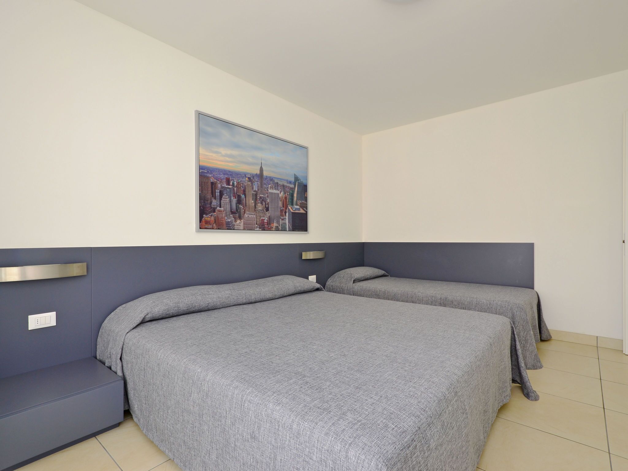 Une chambre d’hôtel avec deux lits, un tableau représentant un paysage urbain accroché au mur et un décor moderne.