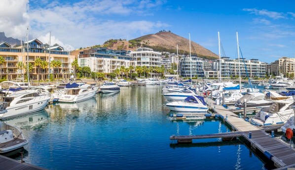 Boats docked in a picturesque marina, surrounded by buildings with balconies.