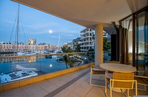 Enjoy the serene marina views from this balcony with a table and chairs.