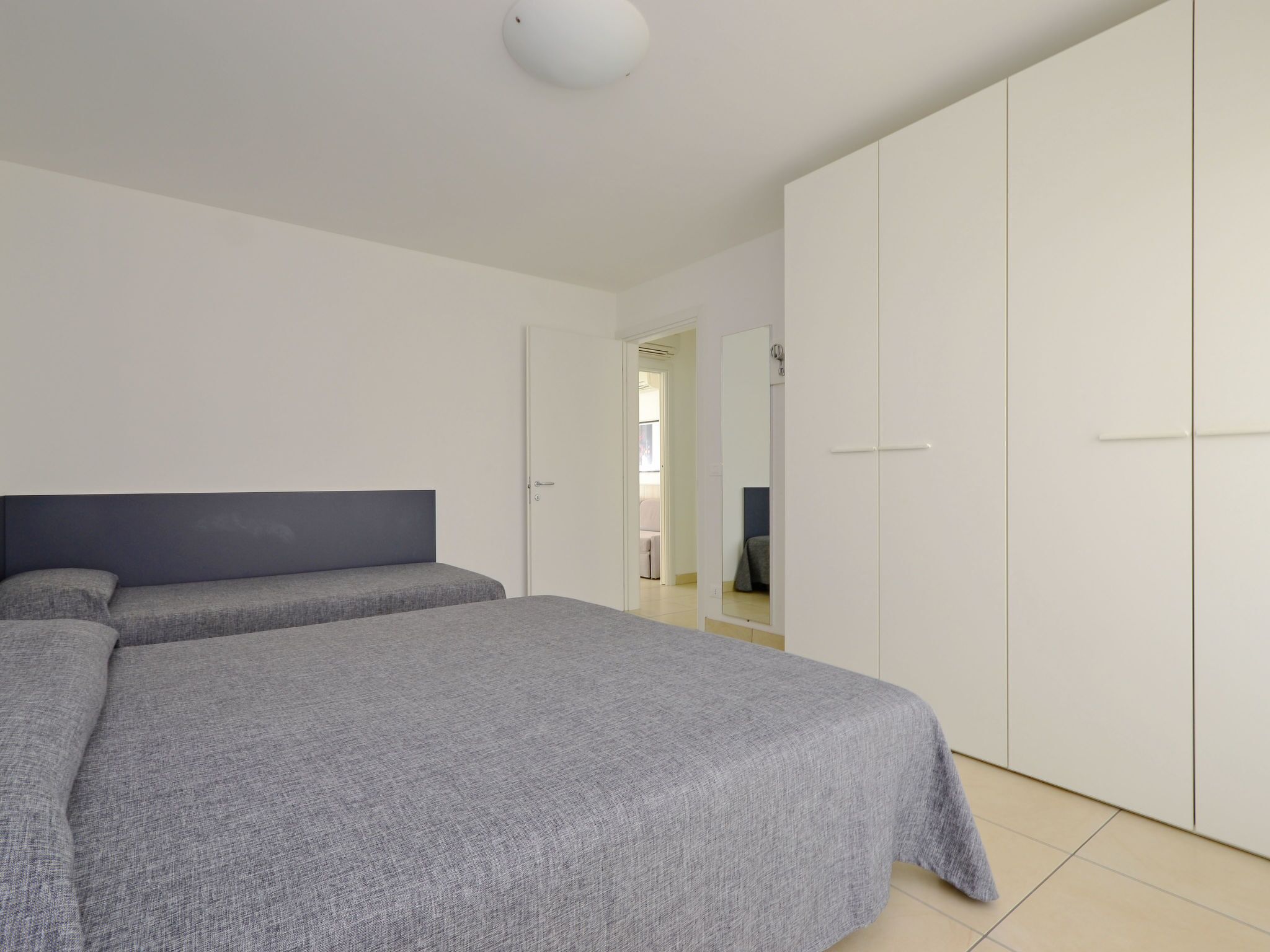 Une chambre à coucher avec un grand lit, une armoire et une porte donnant sur une autre pièce.