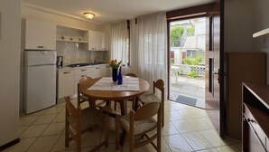 Cocina compacta con comedor, refrigerador, estufa y mesa dispuesta para cuatro.