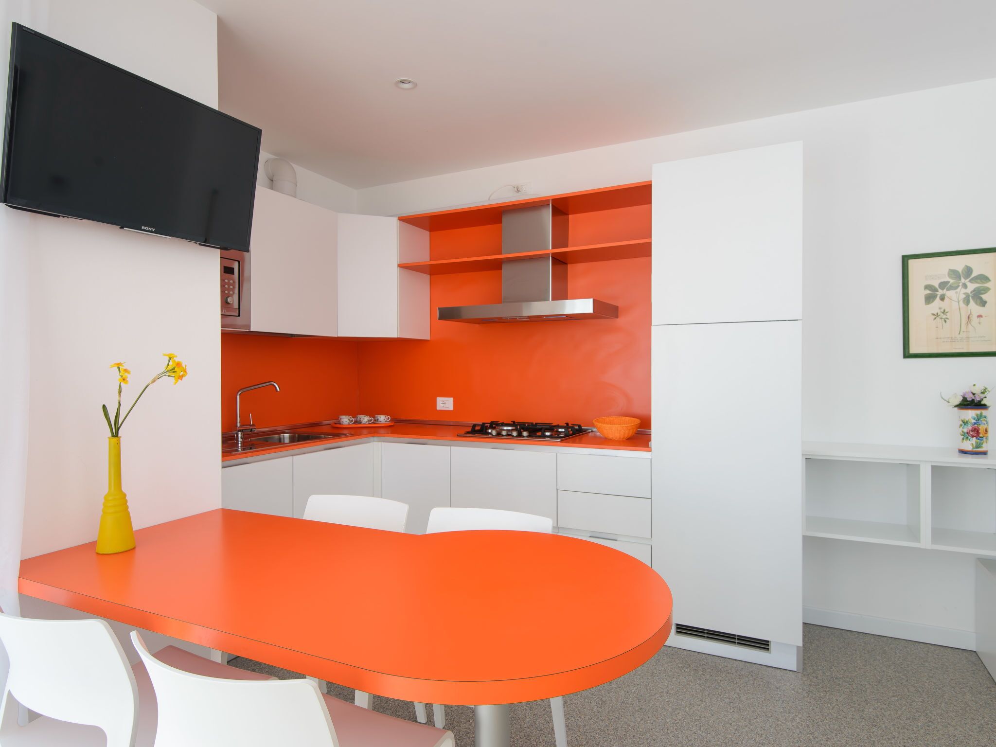 Una cucina moderna con pensili bianchi, un piano di lavoro arancione e una cucina a gas integrata.