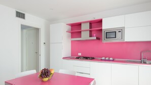 A modern kitchen with white cabinets, a pink countertop, and a microwave.