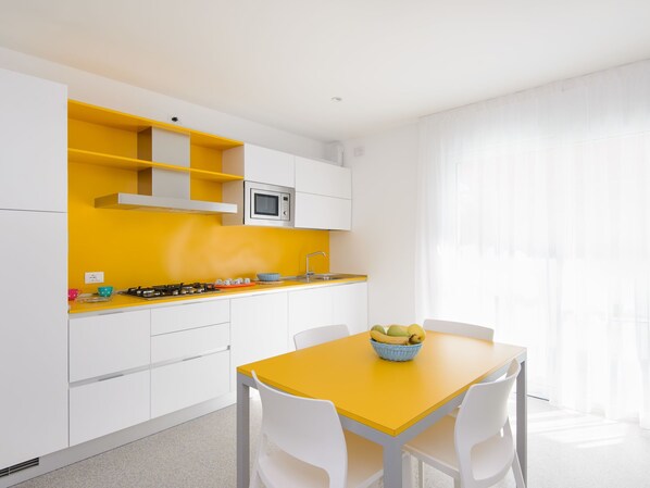 Una cocina moderna con armarios blancos, una encimera amarilla y una mesa de comedor con sillas.