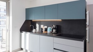 A modern kitchen with a black countertop, white cabinets, and a blue accent wall. - Nashira by Interhome (Lignano Sabbiadoro)