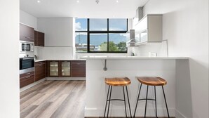 Eine moderne Küche mit einem großen Fenster, Holzhocker und integrierten Geräten.