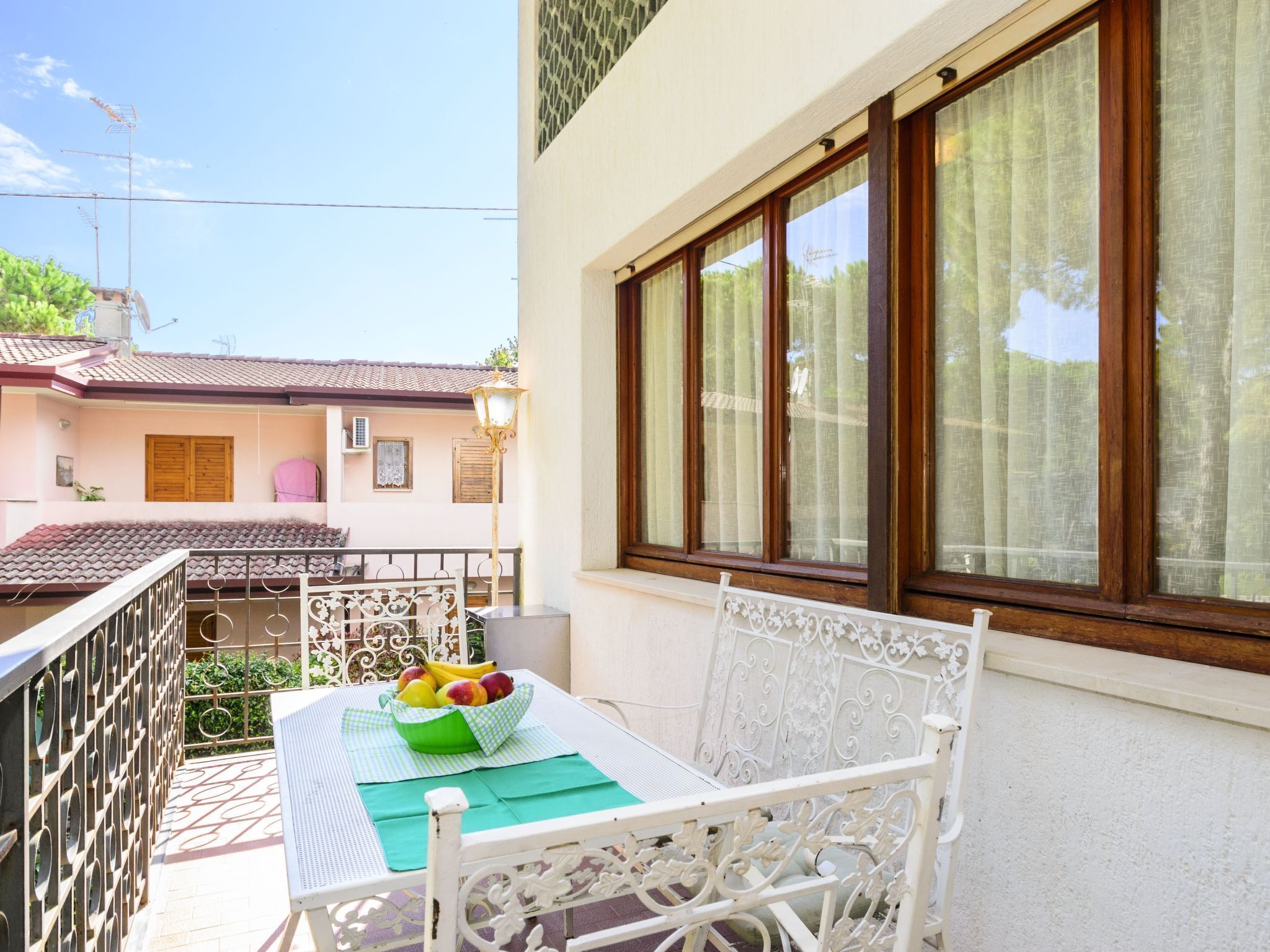 A balcony with a table, a chair, and a bowl of fruit.