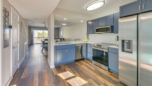 Een moderne keuken met roestvrijstalen apparatuur, blauwe keukenkastjes en een houten vloer.