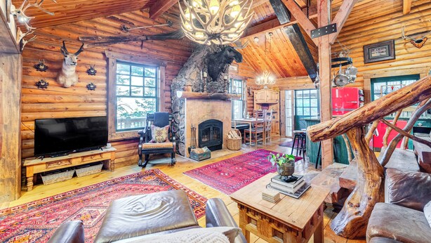 Un interno rustico di una baita con camino, pareti in legno, mobili in pelle e decorazioni con corna di cervo.