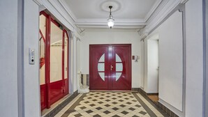 A hallway with a checkered floor, a red door with glass panels, and a light fixture on the ceiling. - Apartment in the Center of Paris by Studioprestige (Paris)