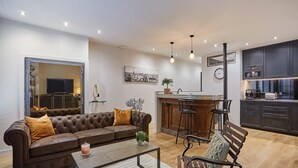 A modern living room with a brown sofa, a coffee table, and a bar area with stools. - Apartment in the Center of Paris by Studioprestige (Paris)