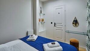 A modern bedroom with a bed, a glass shelf with toiletries, a white door, and a mirror on the wall. - Apartment in the Center of Paris by Studioprestige (Paris)