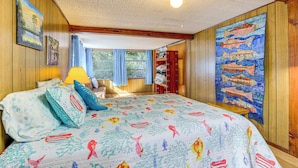 Ein Schlafzimmer mit Bett, Holzwänden, einem Fenster mit Vorhängen, einem Fischgemälde und einer Deckenleuchte.
