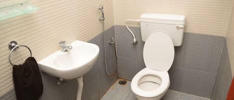 Une petite salle de bain avec un lavabo, des toilettes et une douche, le tout de couleur blanche.