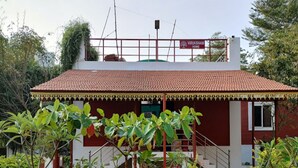 Uma casa vermelha com telhado de telhas, uma escadaria e uma placa com a inscrição 'Virukshan Home'.