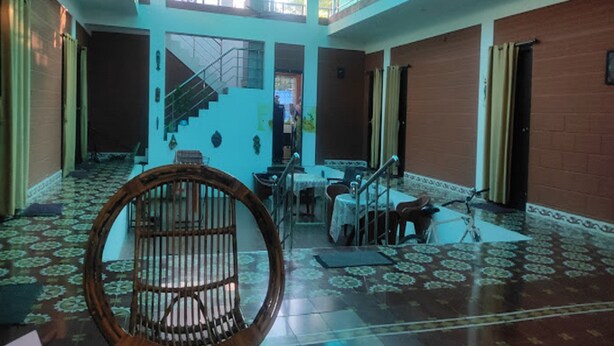 Um hall amplo com teto alto, escadaria central e piso estampado.