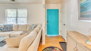 Un salón con un sofá seccional color beige, una mesa de centro y una puerta que conduce a otra habitación.