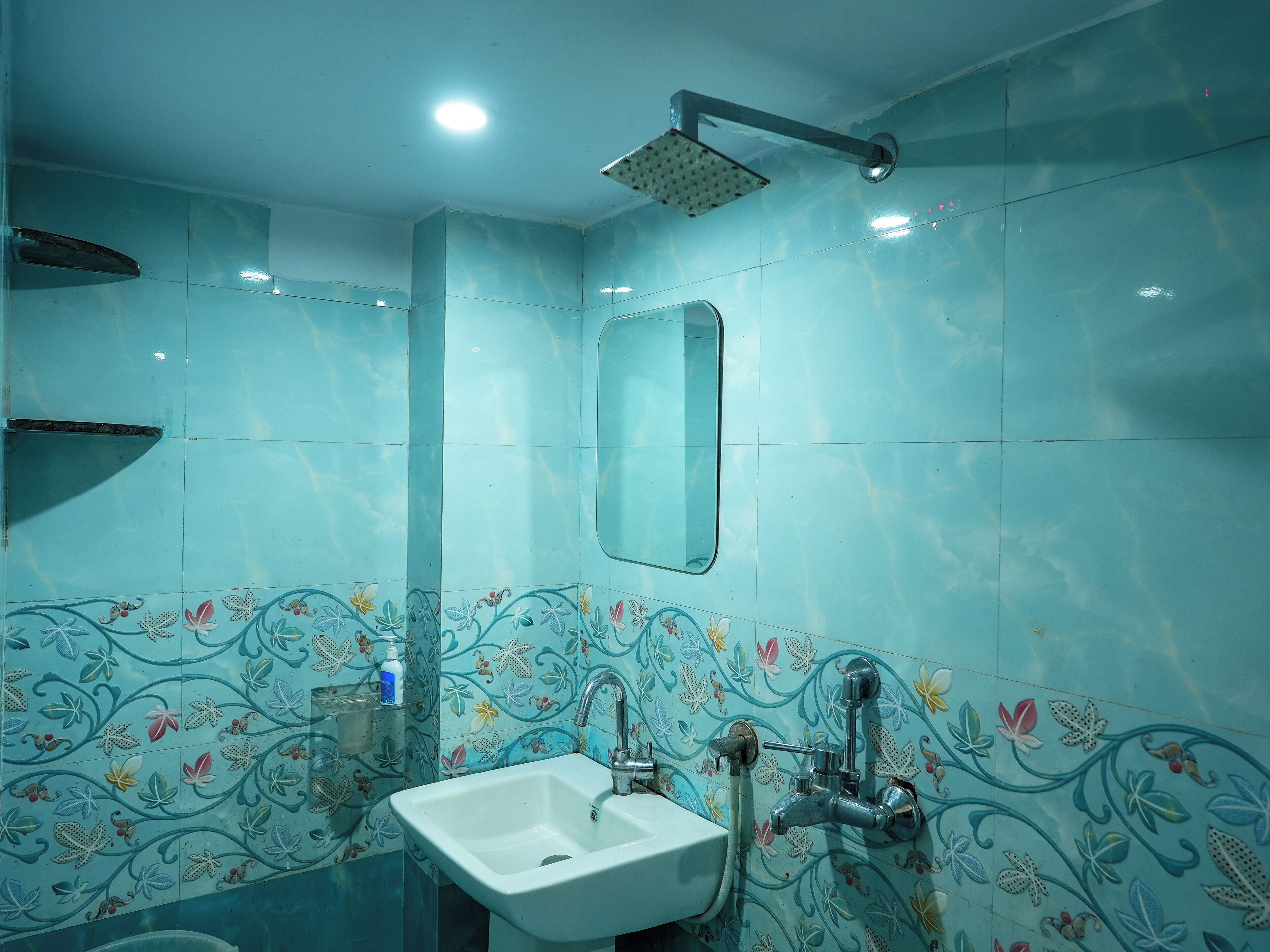 Een badkamer met een wastafel, spiegel en douche.
