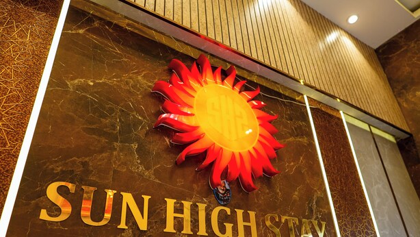 A sign for Sun High Stay Luxury Guest House with a sun emblem. - Sun High Stay Luxury Guest House (Varanasi)