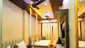 A hotel room with a bed, a desk, a chair, and a ceiling fan. - Sun High Stay Luxury Guest House (Varanasi)