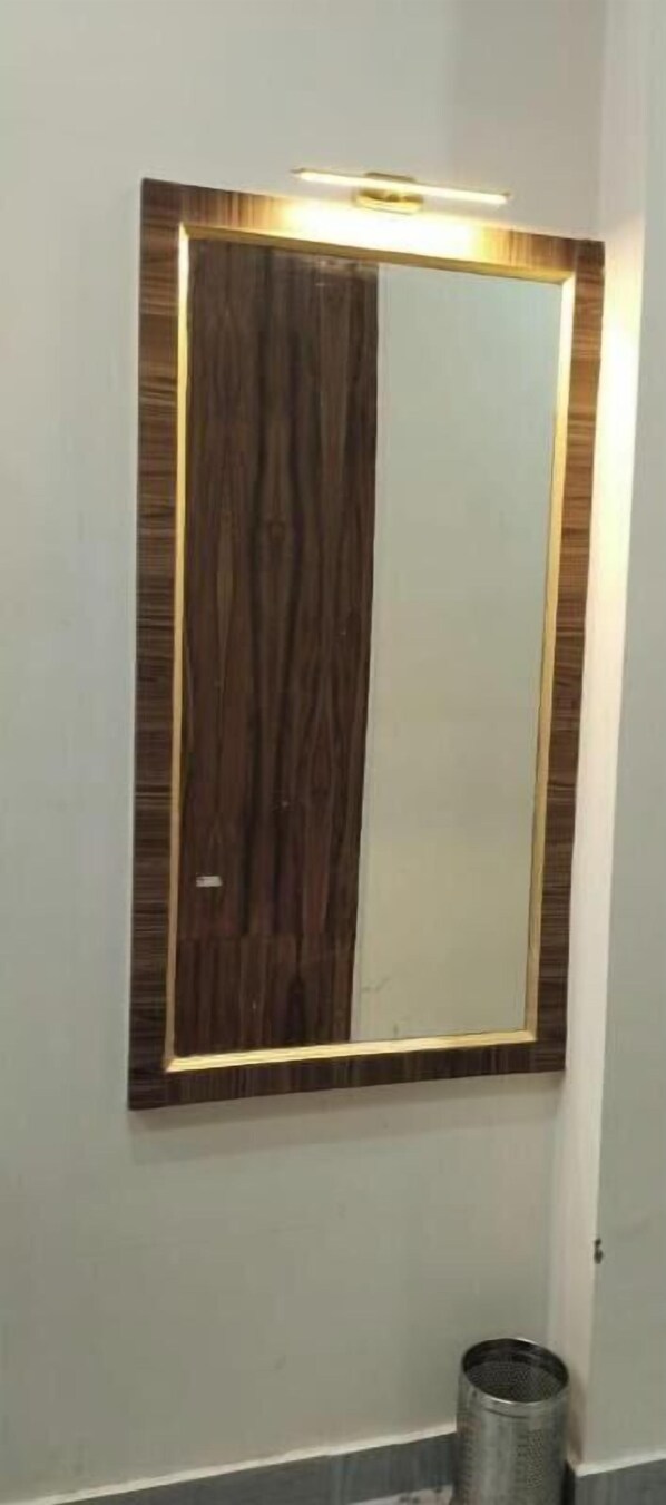A bathroom with a large mirror and a small trash can.
