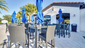 Terrasse mit Korbstühlen und blauen Sonnenschirmen an einer Bar und Lounge namens 'Tu Casa'.
