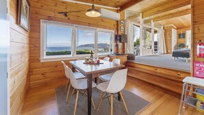A wooden cabin with a dining area, large windows, and a view of the sea. - 3 Oaks on the Lake -  Kinloch (Kinloch)