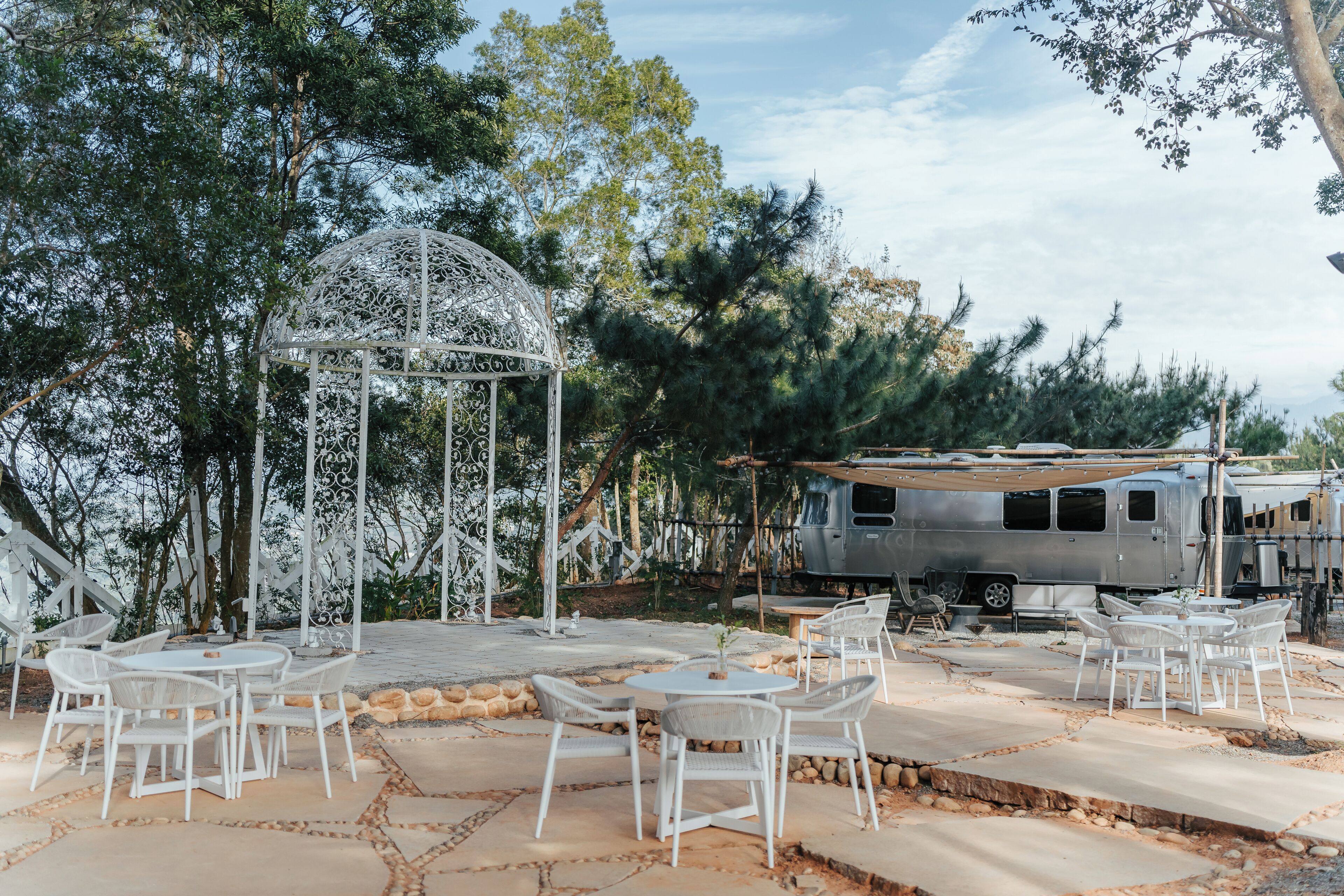 An outdoor seating area with white wicker furniture and a decorative metal gazebo.