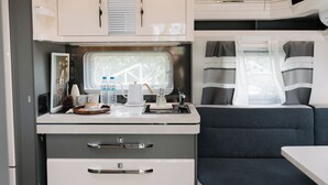 A compact RV interior with a kitchenette, a dining area, and a sleeping berth. - Le.Alley Autocamp Resort (Zhuolan)
