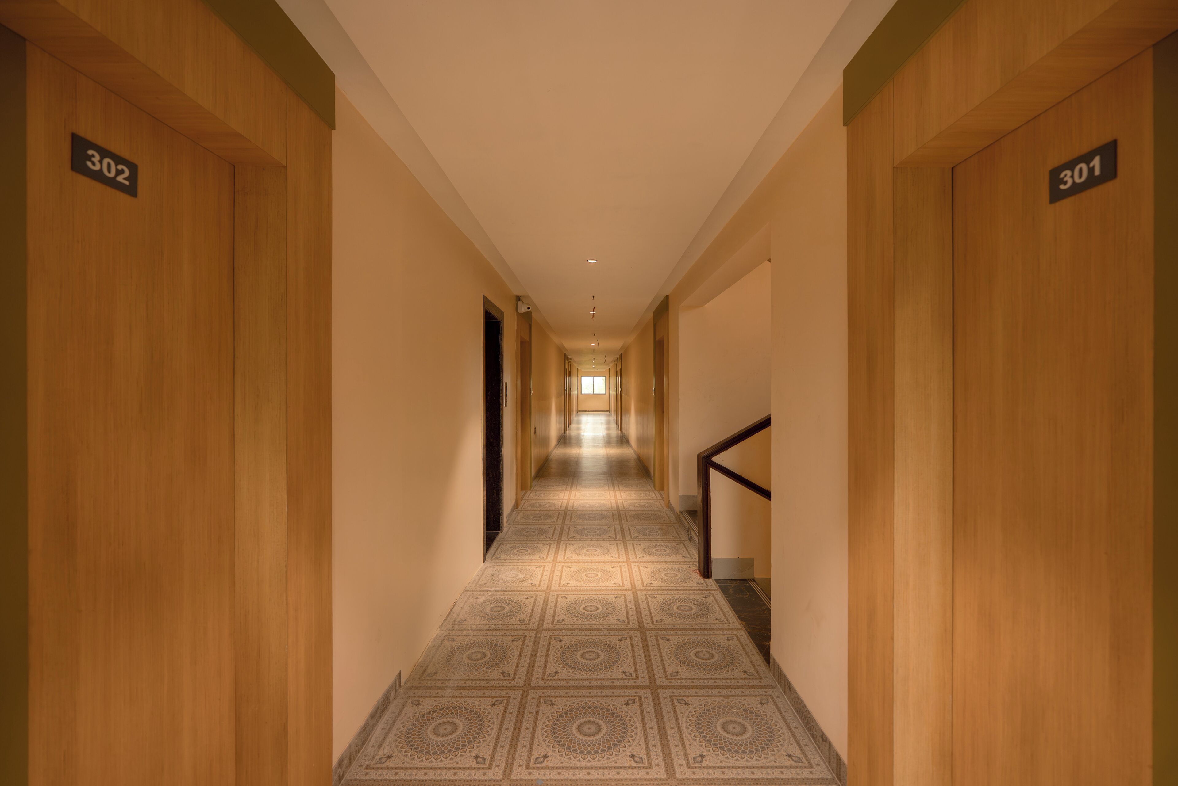 A hallway with wooden doors numbered 302 and 301, leading to a bright room at the end.