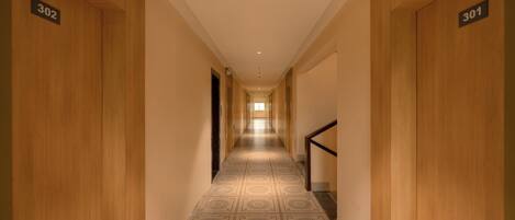 A hallway with wooden doors numbered 302 and 301, leading to a bright room at the end.