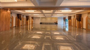 Ένας ευρύχωρος χώρος υποδοχής με γυαλιστερό μαρμάρινο δάπεδο, ξύλινα διακοσμητικά στοιχεία και μεγάκυκλους πολυελαίους.