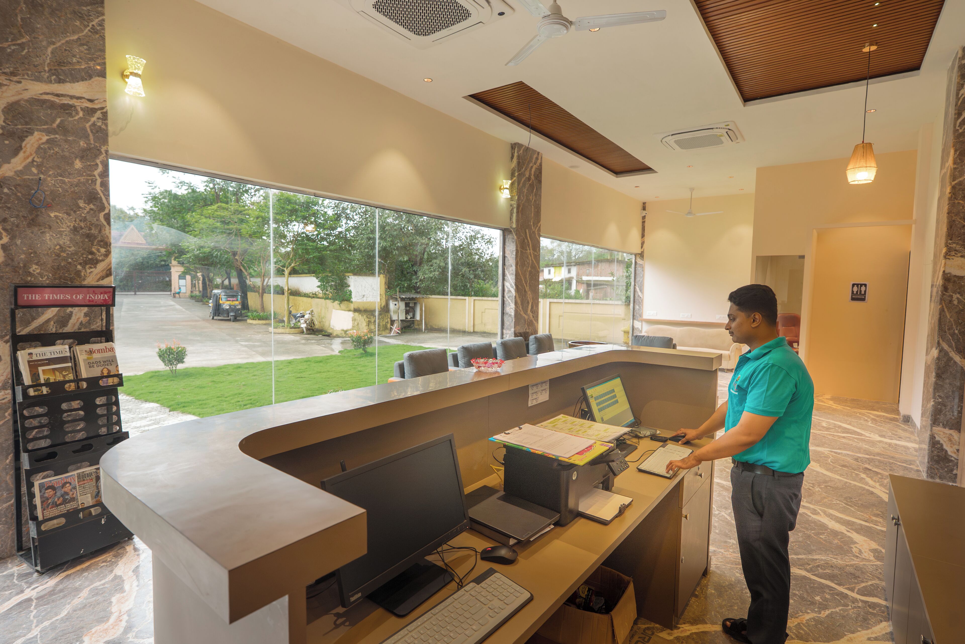 A reception desk with multiple computer stations, a newspaper rack, and a view of the outside.