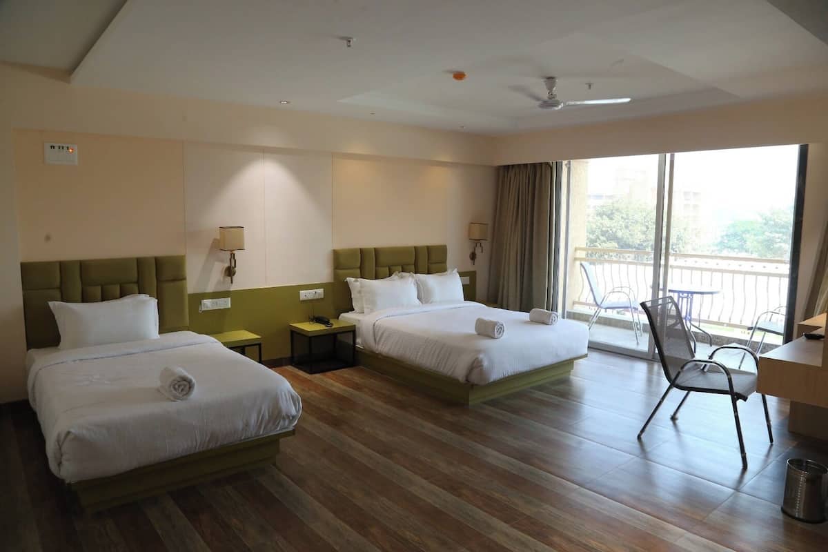 Habitación de hotel con dos camas, un escritorio, una silla y un balcón con mobiliario exterior.