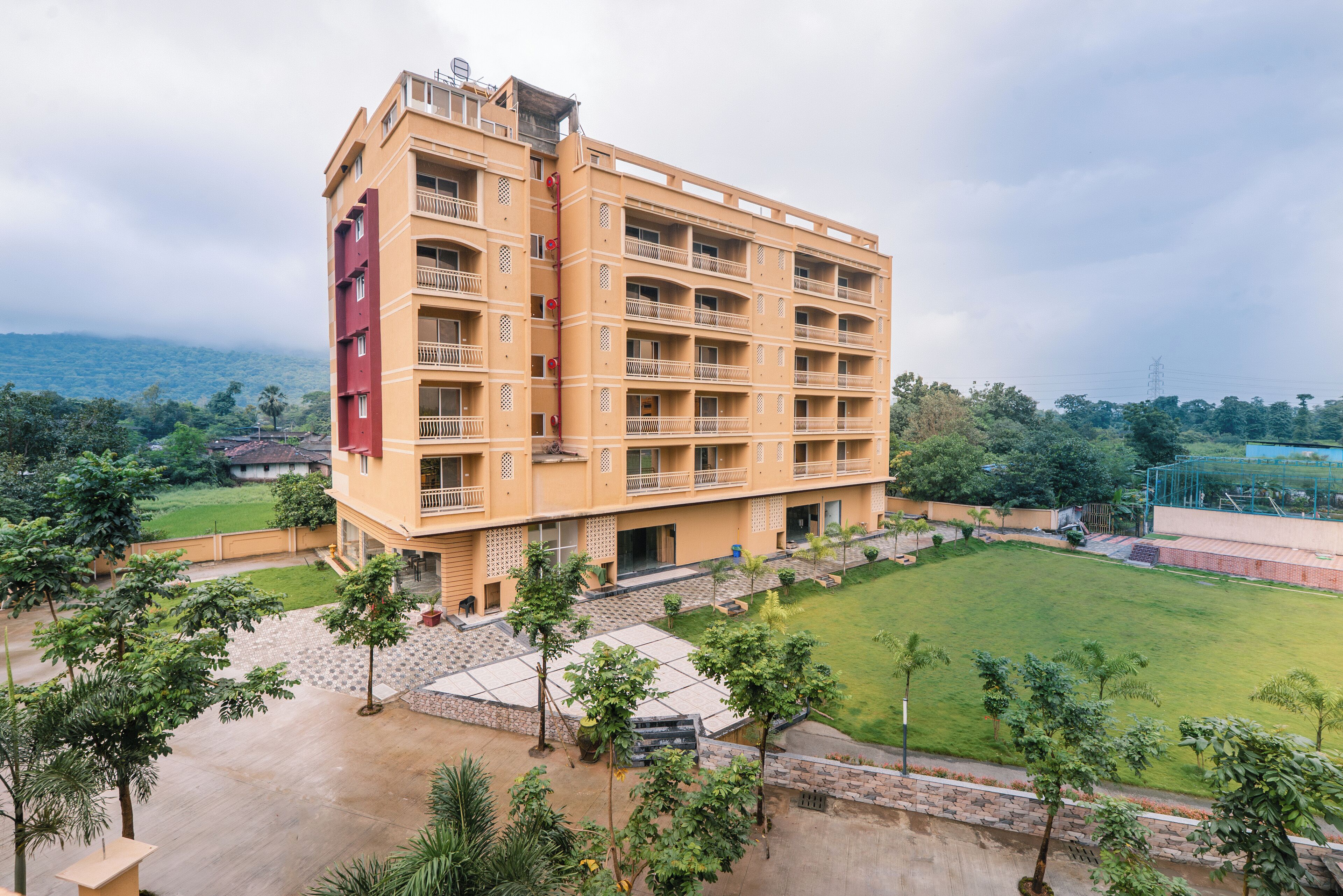 A multi-story hotel with balconies, a courtyard, and a view of the surrounding greenery.