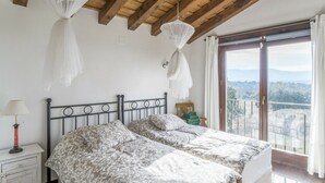 A bedroom with a bed, bedside table, lamp, and a view of the outdoors through a large window. - Finca Montechico, Casa Matute, rural Segovia (Segovia)