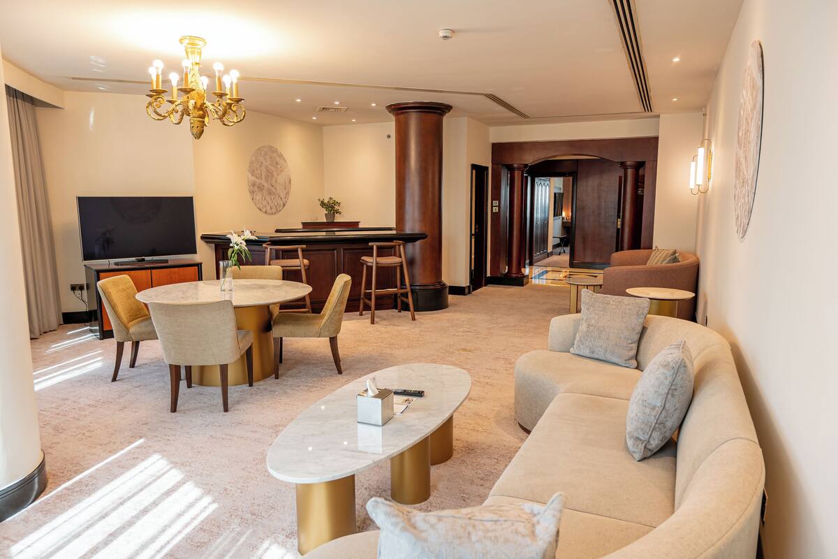 Een moderne hotelkamer met een zithoek, een eettafel, een bank en een televisie.