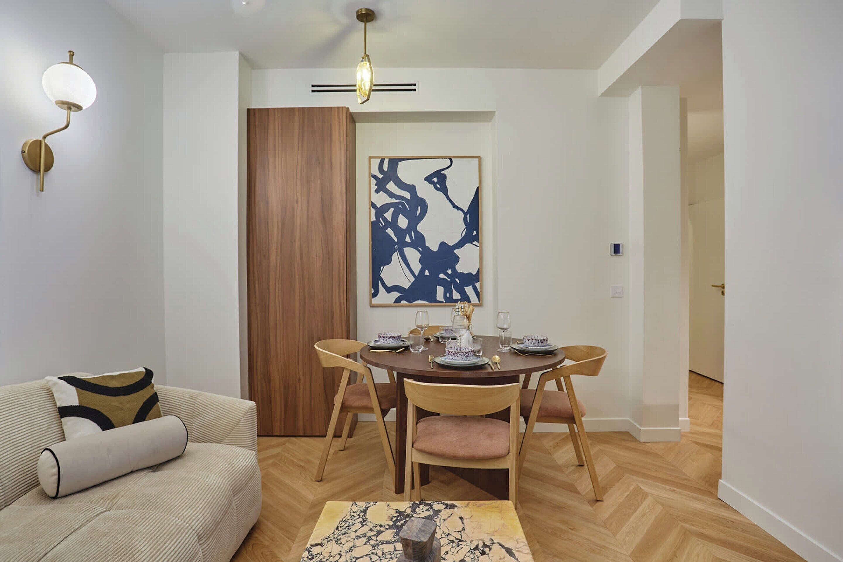 A dining area with a wooden table, chairs, and a modern light fixture.