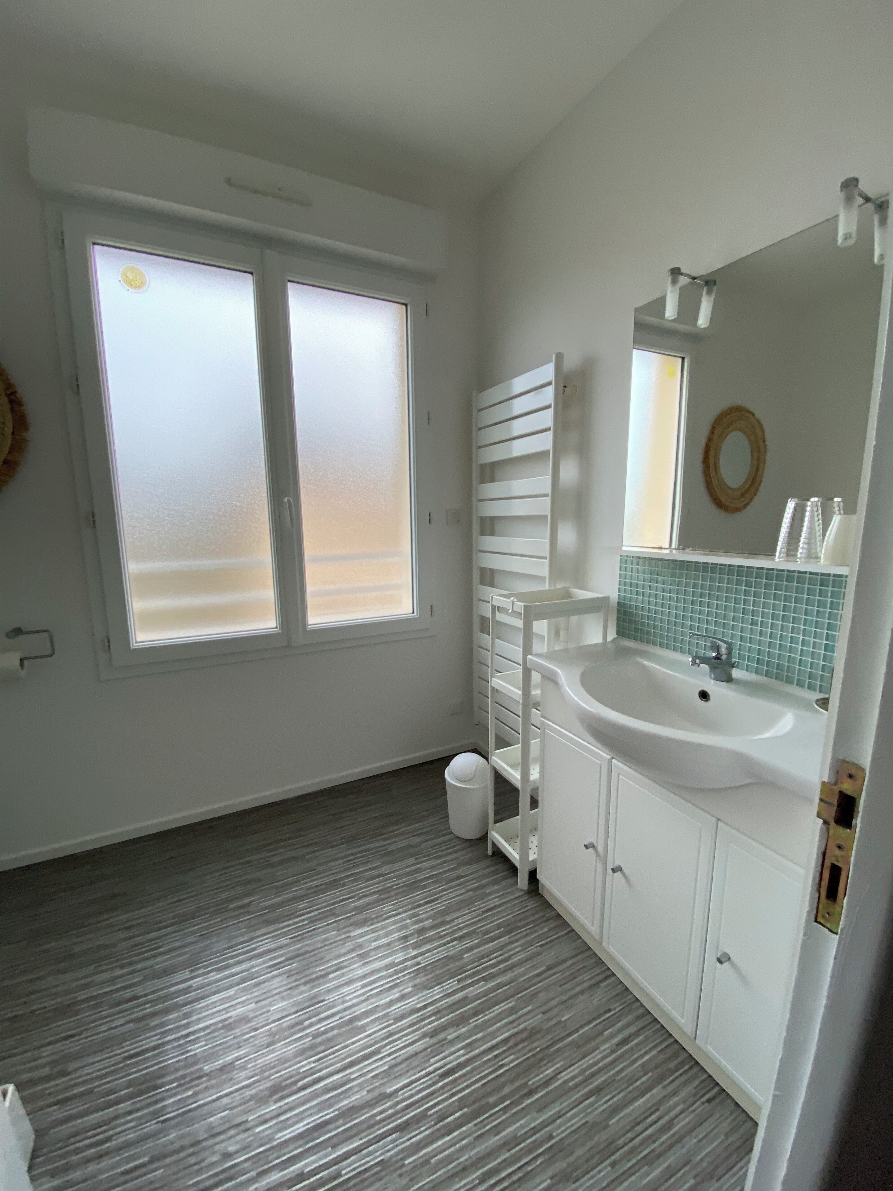 Un baño con un ventanal grande, un lavabo y un espejo.