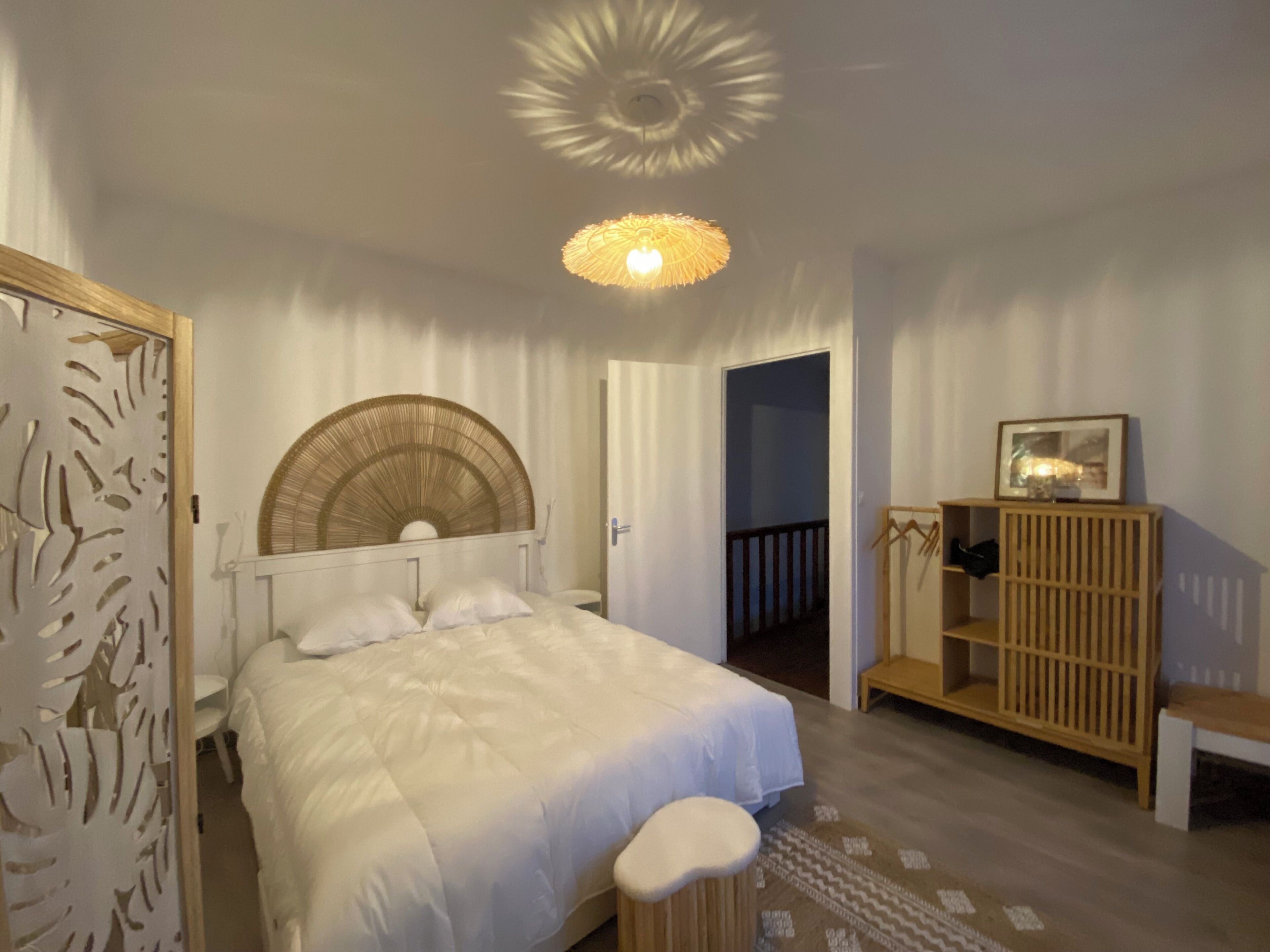 A bedroom with a bed, a bedside table, a wardrobe, and a ceiling light fixture.