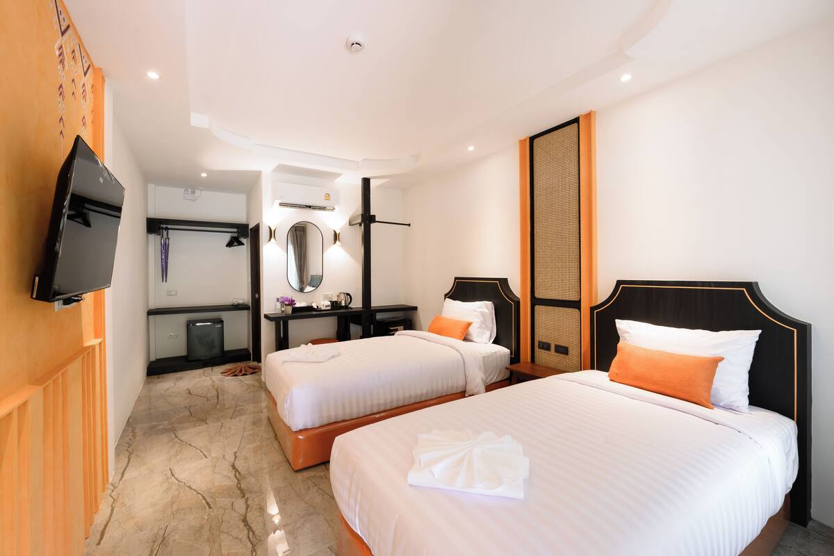 Une chambre d’hôtel avec deux lits, une télévision, un bureau avec un ordinateur et un miroir.