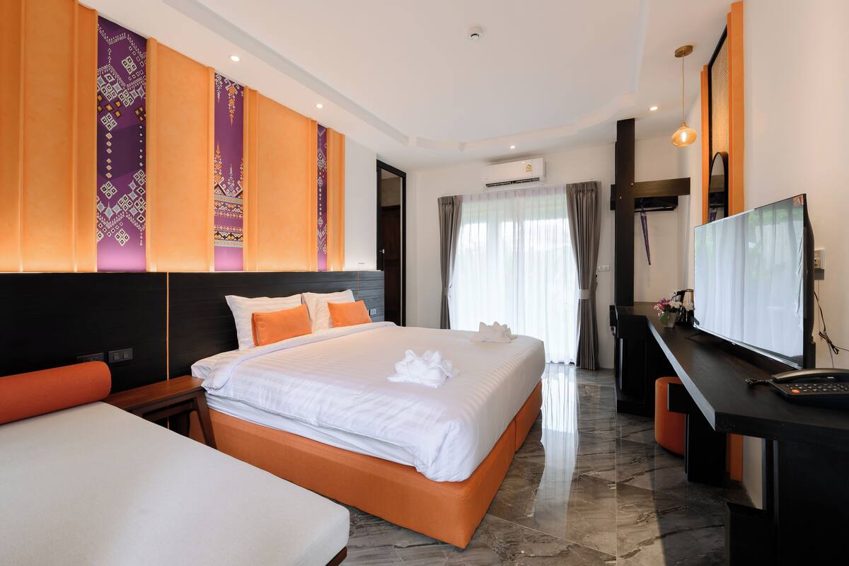 Une chambre d’hôtel moderne équipée d’un grand lit, d’un bureau avec un ordinateur et d’une télévision.