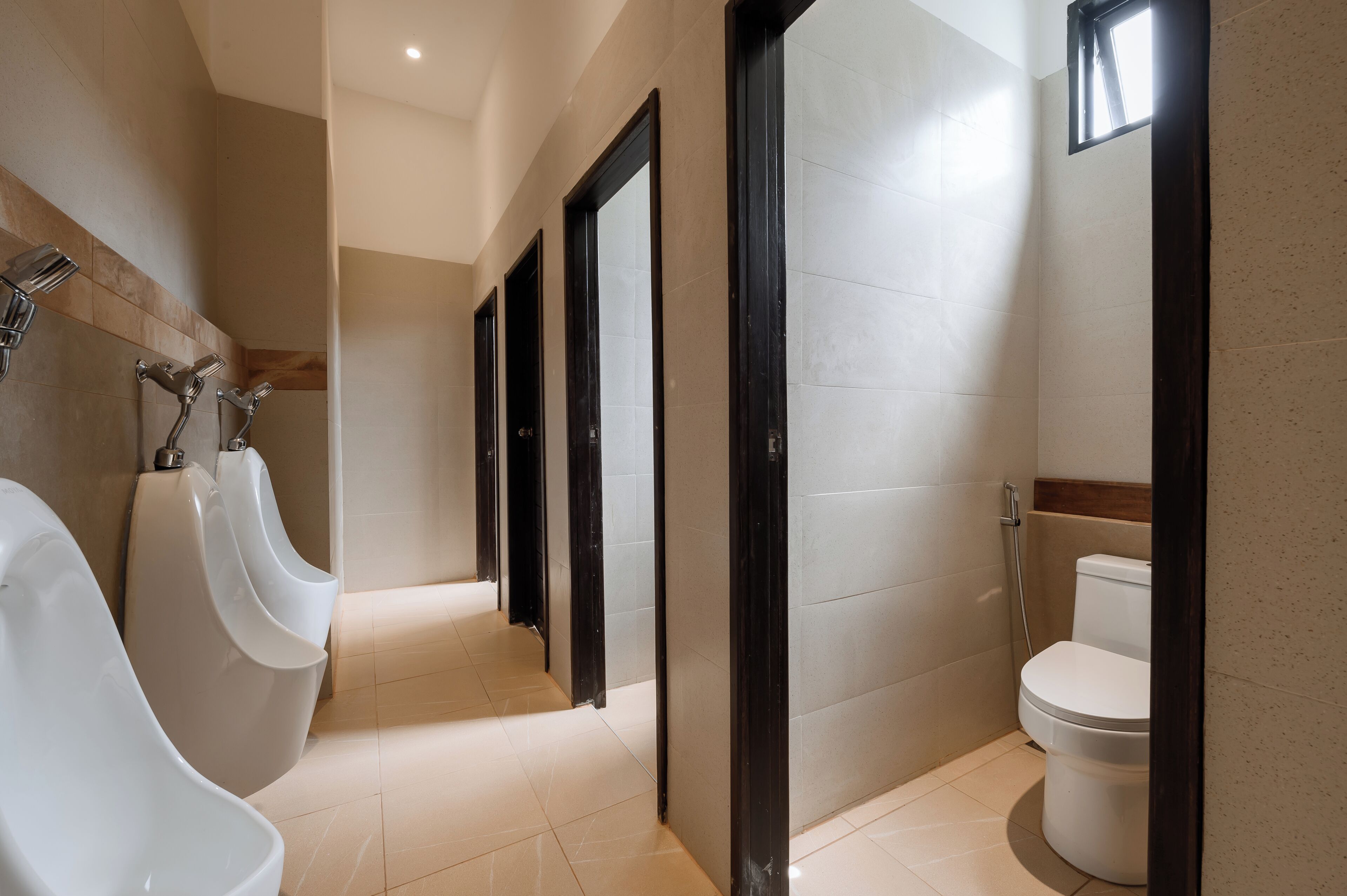 Un baño moderno con orinales, inodoro y zona de ducha.