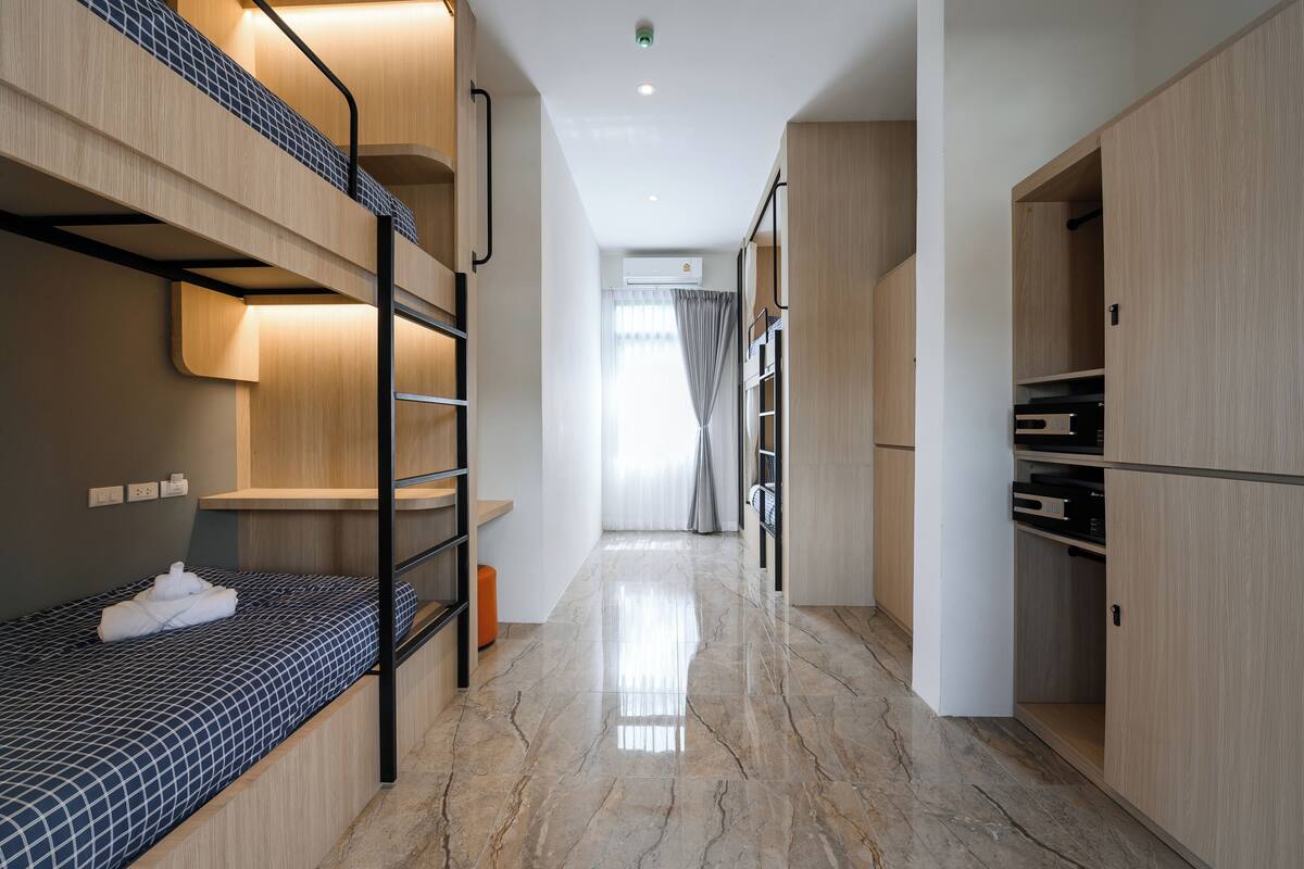 Une chambre d’hôtel moderne équipée de lits superposés, d’une armoire et d’une salle de bain avec douche.
