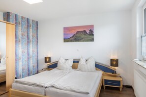 Een slaapkamer met een bed, twee nachtkastjes, een wandlamp en een schilderij.